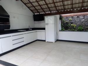 a kitchen with white cabinets and a refrigerator at LUXO E CONFORTO NO CENTRO in Campos dos Goytacazes