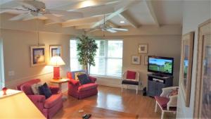 a living room with red chairs and a flat screen tv at GUIDING LIGHT UNIT C - GROUNDFLOOR apts in Jekyll Island