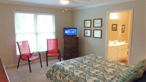 a bedroom with a bed and two chairs and a television at GUIDING LIGHT UNIT C - GROUNDFLOOR apts in Jekyll Island