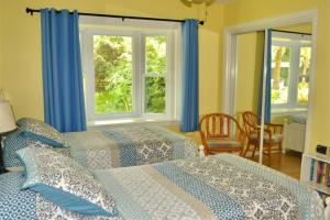 een slaapkamer met 2 bedden en 2 ramen bij A JEKYLL INTERLUDE home in Jekyll Island