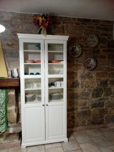 a white cabinet with dishes in it against a brick wall at La tana delle coccinelle in Capracotta