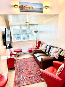 een woonkamer met een bank en rode stoelen bij The Upper Bakery in Cromer