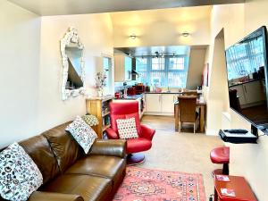 a living room with a leather couch and a kitchen at The Upper Bakery in Cromer