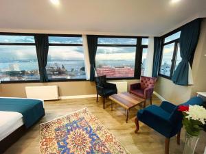 ein Schlafzimmer mit einem Bett und Stühlen sowie großen Fenstern in der Unterkunft Cape Palace Hotel in Istanbul