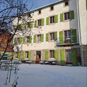 a building with green shuttered windows and a courtyard at Le Grenier des Moineaux Chezchristineetfabrice in Odeillo-Via