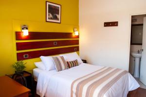1 dormitorio con cama blanca y pared amarilla en Casa de Avila, en Arequipa
