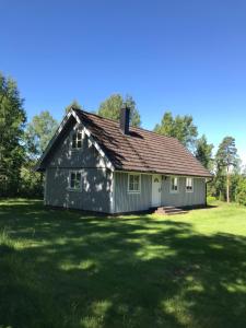 una casa su un campo erboso con alberi sullo sfondo di Lake and Forest Hideaway a Årjäng