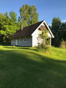 een klein wit huis met een groot grasveld bij Lake and Forest Hideaway in Årjäng