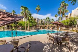 a resort pool with tables and chairs and palm trees at Groovy Old Town Scottsdale Condo in Scottsdale