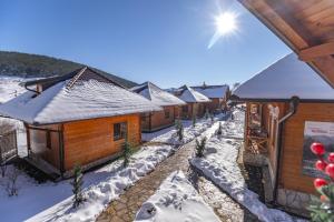 a row of wooden cabins in the snow at Kedar selo Goč in Goč