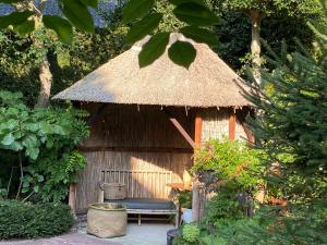 une petite cabane avec un banc et un toit de chaume dans l'établissement De Schuilhoek Private Guesthouse, à Blaricum