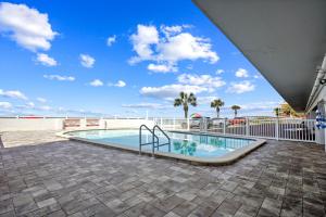 a swimming pool with a blue sky and palm trees at Sunset Chateau 409 in St Pete Beach