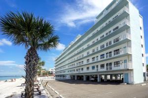 a large white building next to a palm tree at Sunset Chateau 409 in St Pete Beach