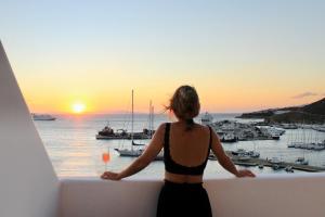 a woman standing on a balcony with a glass of wine at Calistus Mykonos in Mikonos
