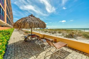 a patio with chairs and an umbrella and the beach at Villa Madeira 410 in St. Pete Beach