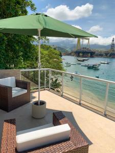 a patio with an umbrella and chairs and the water at Casa Martureza in Angra dos Reis