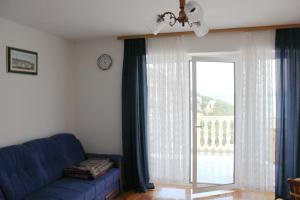 ein Wohnzimmer mit einer blauen Couch und einem großen Fenster in der Unterkunft Apartments Toni Na Moru in Drage