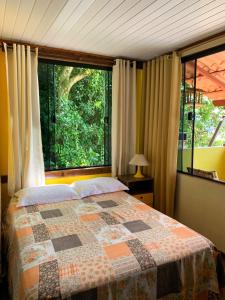 1 dormitorio con cama y ventana grande en Casa Martureza, en Angra dos Reis