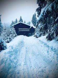 a snow covered road in front of a house at chata REINA in Pusté Pole