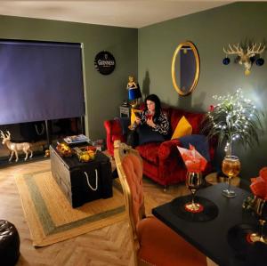 a woman sitting on a couch in a living room at Wee Hoose-Private-Hottub -Romantic Break-Portaferry in Kearney