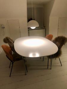 a white table with furry chairs and a light at Nyhavn Apartment in Copenhagen