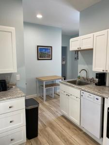 a kitchen with white cabinets and a sink and a table at Hasty House Studio in Auburn