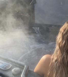 Una donna seduta in una vasca da bagno piena di vapore di Wee Hoose-Private-Hottub -Romantic Break-Portaferry 