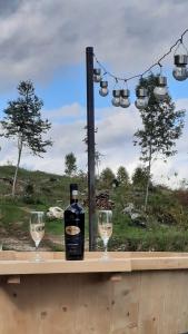 Una botella de vino y dos copas en una mesa. en Cabana Himalaya Lodge cu ciubăr din inima munților Apuseni- masivul Buces -Vulcan, 
