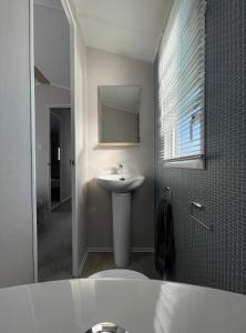 a bathroom with a white sink and a mirror at Newperran 102 in Cubert