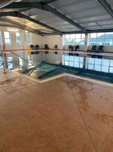 an empty swimming pool with tables and chairs in a building at Newperran 102 in Cubert