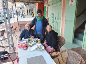 un grupo de tres personas sentadas en una mesa en Auberge Restaurant Rooftop Tamazirt, en Boumalne