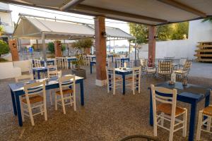 een groep tafels en stoelen met parasols bij Ilioxenia Chios Studios & Apartments in Paralia Agias Foteinis