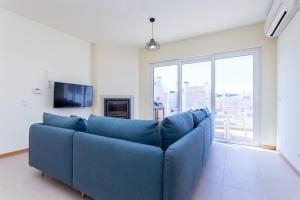 um sofá azul numa sala de estar com uma grande janela em Burgau 2floor appt in condominium w/ shared pool no Burgau