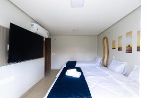 a room with a bed and a flat screen tv at Casa Sirenia in Cajueiro