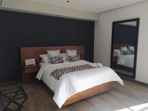 1 dormitorio con 1 cama grande y espejo grande en Hotel Monarca San Luis Potosí, en San Luis Potosí