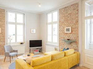 a living room with a yellow couch and a brick wall at OSTKÜSTE - Villa Groth Design Apartments in Heringsdorf