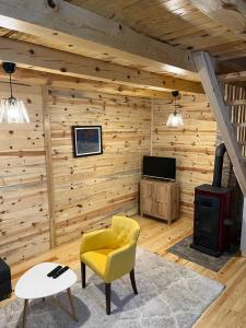 un soggiorno con pareti in legno, una sedia gialla e una stufa di Apartments Milev a Mokra Gora