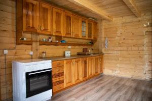 a kitchen with a stove and wooden cabinets at Mariash Woodhouse - Beleg Mountains in Deçan