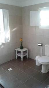 a bathroom with a toilet and a vase with a flower in it at Casa Lola in Barra de Valizas