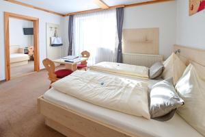 a bedroom with two beds and a desk and a room with a bed at Hotel Sonnfeld in Hinterstoder