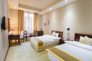 Cette chambre comprend deux lits et un bureau. dans l'établissement Diamond Hotel Yerevan, à Erevan