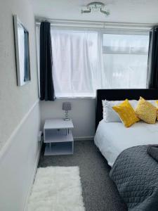 a bedroom with a bed with yellow pillows and a window at Aylesbury Apartment for Contractors and Holidays - FREE Parking for cars and vans in Aylesbury