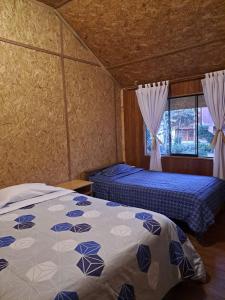 a bedroom with two beds and a window at La Ramada de Mama Elena in Oxapampa