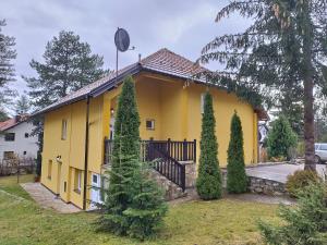 a yellow house with trees in front of it at Apartmani Jokic in Zlatibor