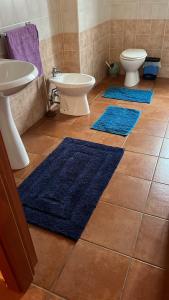 Baño con 3 alfombras azules en el suelo en SantaRufinaHome en LʼAquila