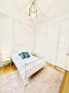 um quarto branco com uma cama com almofadas azuis em Garden Cottage em Geelong