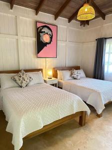 um quarto com duas camas e um quadro na parede em Hotel Villas Gaia Ecolodge em Uvita