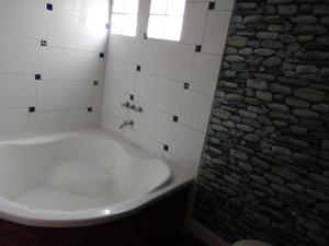 a white bath tub in a bathroom with a stone wall at La Casita de Carla in Quequén +29 photos