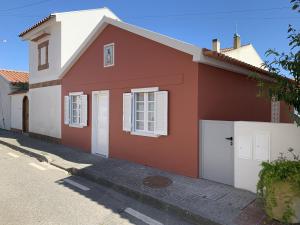 ein rotes und weißes Haus mit weißen Türen in der Unterkunft Torreira Vacation Homes - Ria House in Torreira