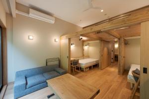 a living room with a blue couch and a bedroom at Hishino Onsen Tokiwakan in Komoro